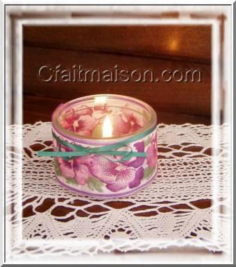 Photophore dans un pot de yaourt en verre bas entour d'un ruban large fleuri, finition avec un fin noeud de ruban vert.