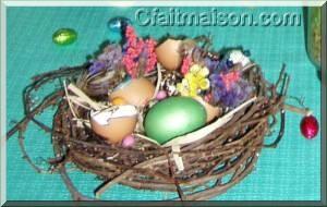 Faux petit nid en vigne vierge avec œufs décorés de fleurs séchées.