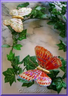 Papillon en plumes peintes et pailletées.