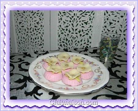 Biscuits roses ronds glacés décorés d'une fleur en pâte d'amandes.
